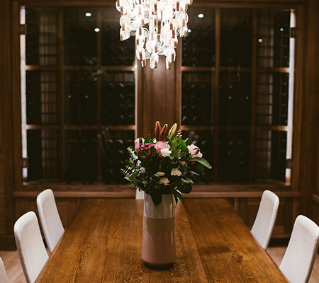 A long table in front of a glass case of old wine bottles